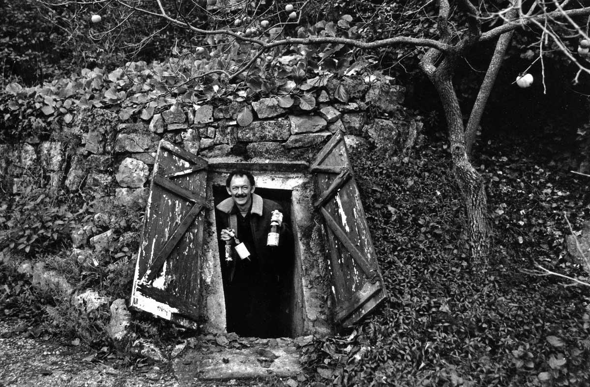 Image of Kermit Lynch emerging from Richard Olney’s cellar with wine bottles